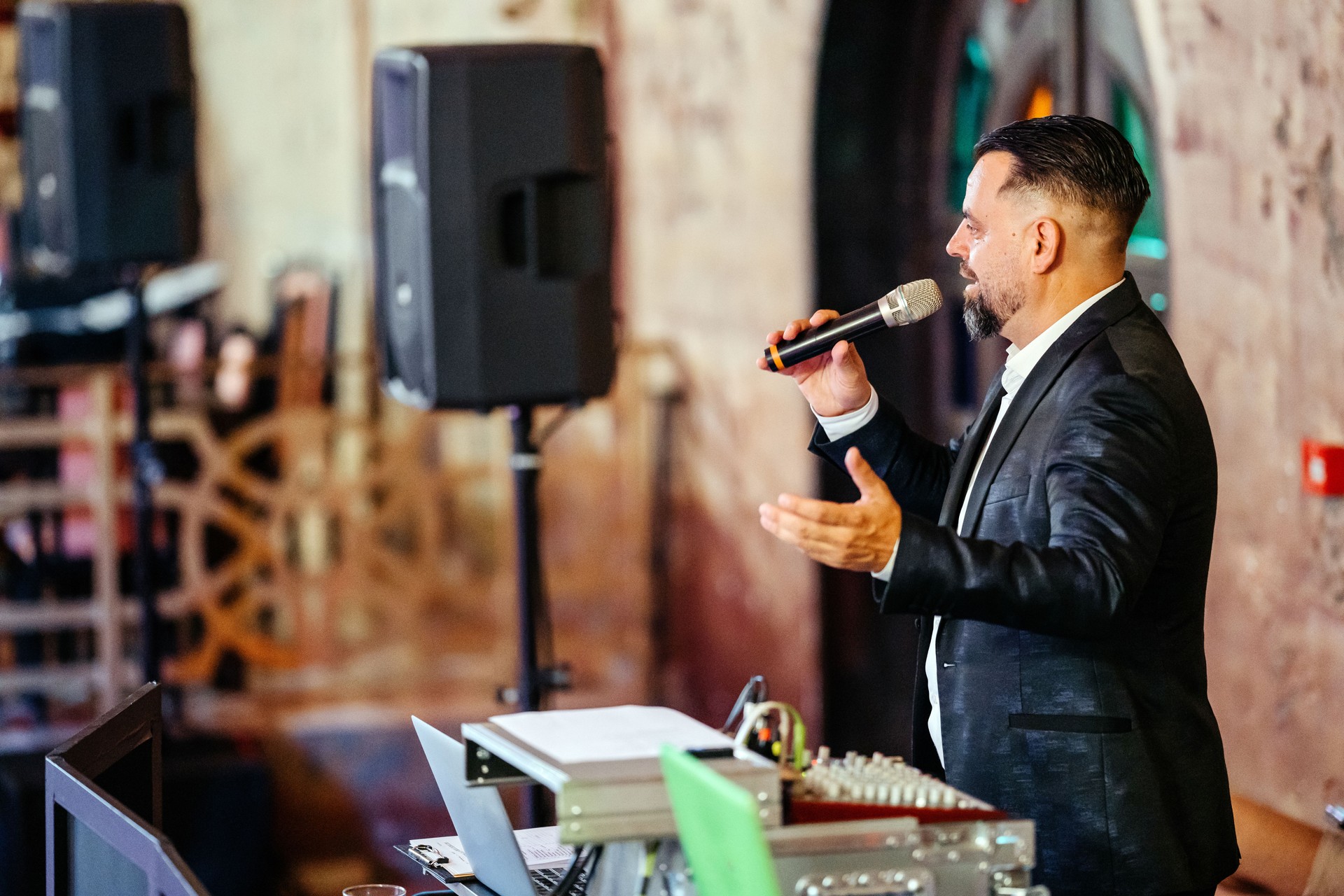 Elegant party host in a black suit holding a microphone on a business party